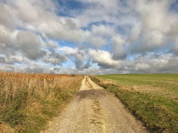 Road amidst agricultural field against sky