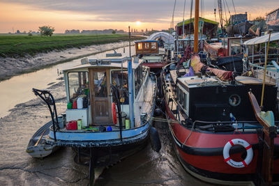 Boats moored at harbor against sky during sunset