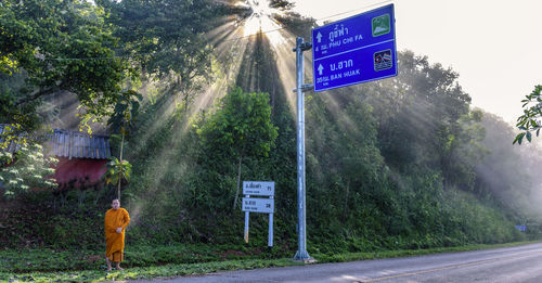 Monk standing by road signs 