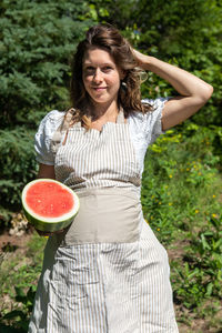 Portrait of woman holding watermelon against tree