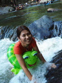 Portrait of smiling woman with inflatable ring swimming in river