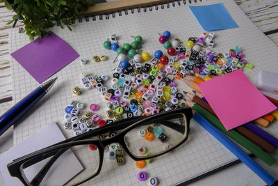 High angle view of alphabet beads with school supplies on paper