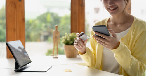 Woman using mobile phone while sitting on table