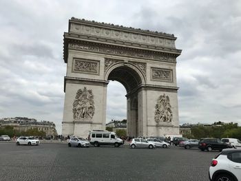 Cars moving on road against cloudy sky