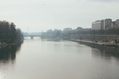 Bridge over river in city against sky