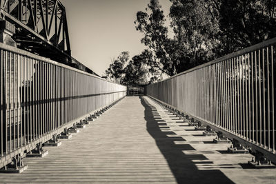 Footbridge amidst trees against clear sky
