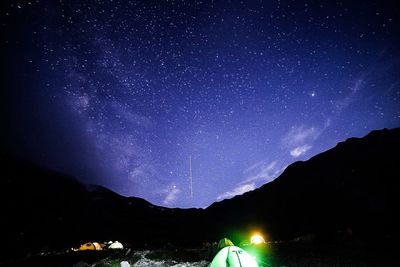 Low angle view of illuminated mountain against star field