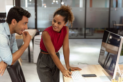 Business people discussing over computer at desk in office