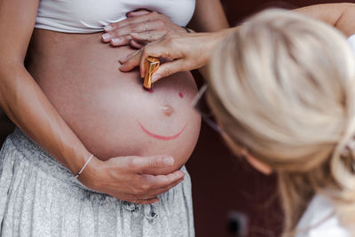 Mother drawing on pregnant daughters abdomen