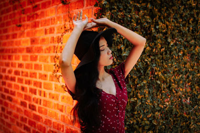 Full length of woman standing against brick wall
