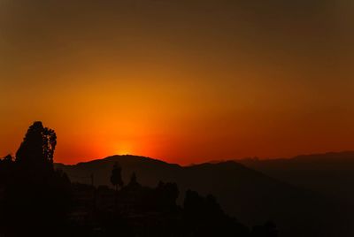 Scenic view of silhouette mountains against orange sky