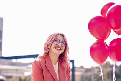 Portrait of a smiling young woman with pink balloons