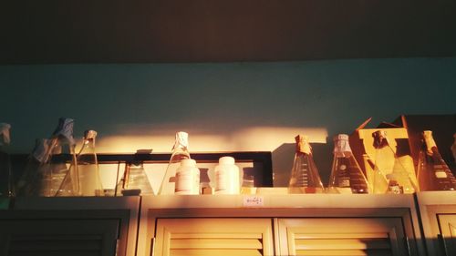 Illuminated lamps on glass table against wall