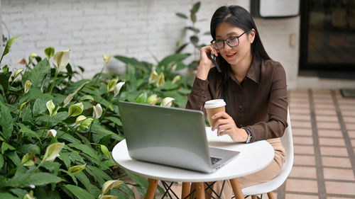 Young woman using phone on table