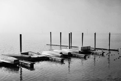 Sailboats moored in sea against sky