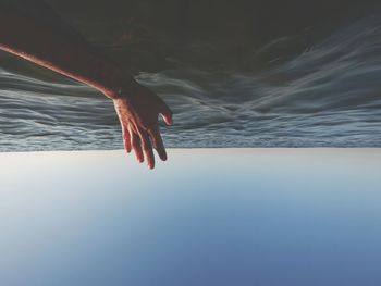 Midsection of person by sea against sky