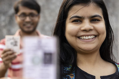 Indian man and woman showing blurred voter card with smile standing in queue