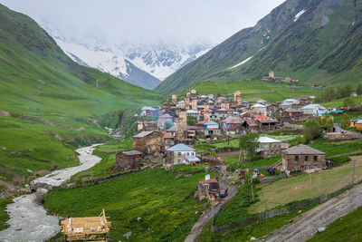 Houses on field by buildings against mountains