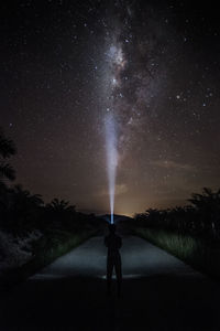 Rear view of silhouette woman standing on field against sky at night