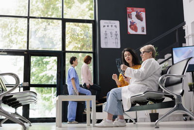 Low angle view of woman using mobile phone while sitting in cafe