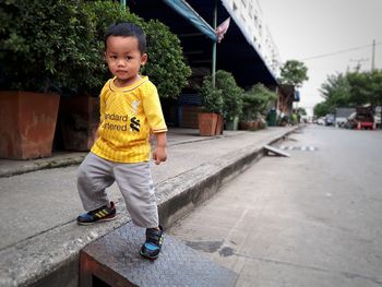 Portrait cute boy standing on footpath