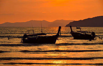 Silhouette boats in sea against sky during sunset