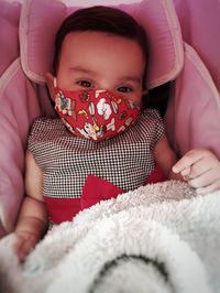 Portrait of cute baby girl lying on bed at home