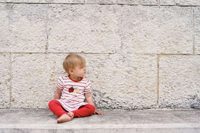 Full length of a boy sitting against wall