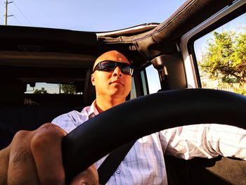 Bald man wearing sunglasses while driving car