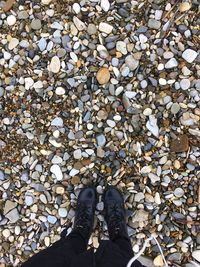 Low section of person standing on pebbles 