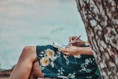 Midsection of woman sitting by sea