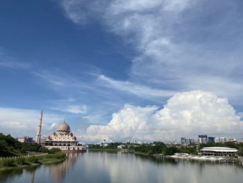 View of temple by lake against cloudy sky