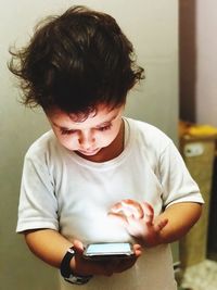 Close-up of boy holding mobile phone at home