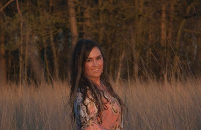 Portrait of smiling young woman standing on field