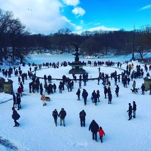 People on snowy field against sky during winter