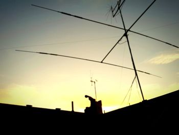 Low angle view of silhouette power lines against sky at sunset