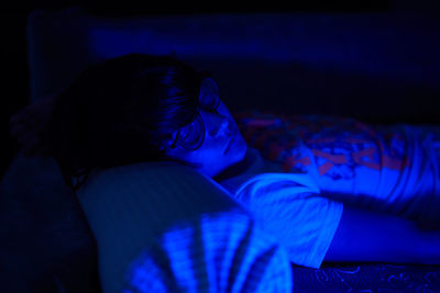 Boy sleeping in illuminated room