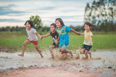 Smiling cute friends running in puddle