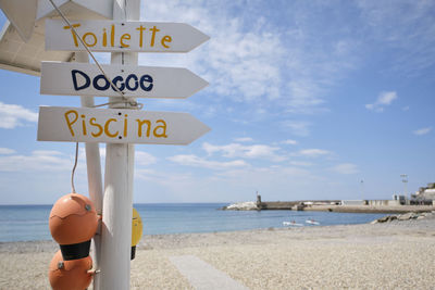 Information sign on beach against sky