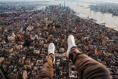 Low section of man sitting in helicopter over buildings in city