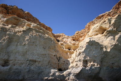 Low angle view of rock formation against clear blue sky