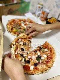 Cropped hand of person preparing pizza