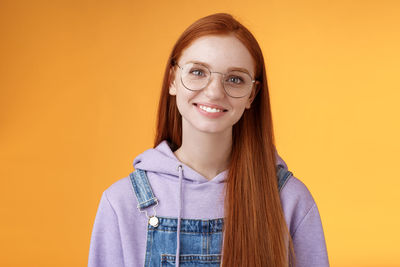 Portrait of a smiling young woman against yellow background