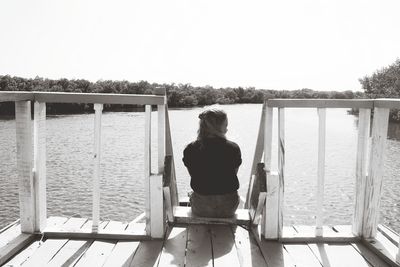 Rear view of woman looking at lake against sky