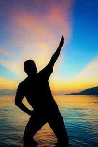 Silhouette man at beach against sky during sunset