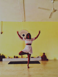 Rear view of woman playing with arms raised standing on floor