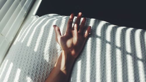 Close-up of hand on bed