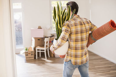 Young man carrying belongings in new home