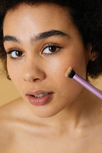 Close-up of young woman applying make-up