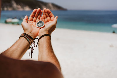 Close-up of hand holding water on beach